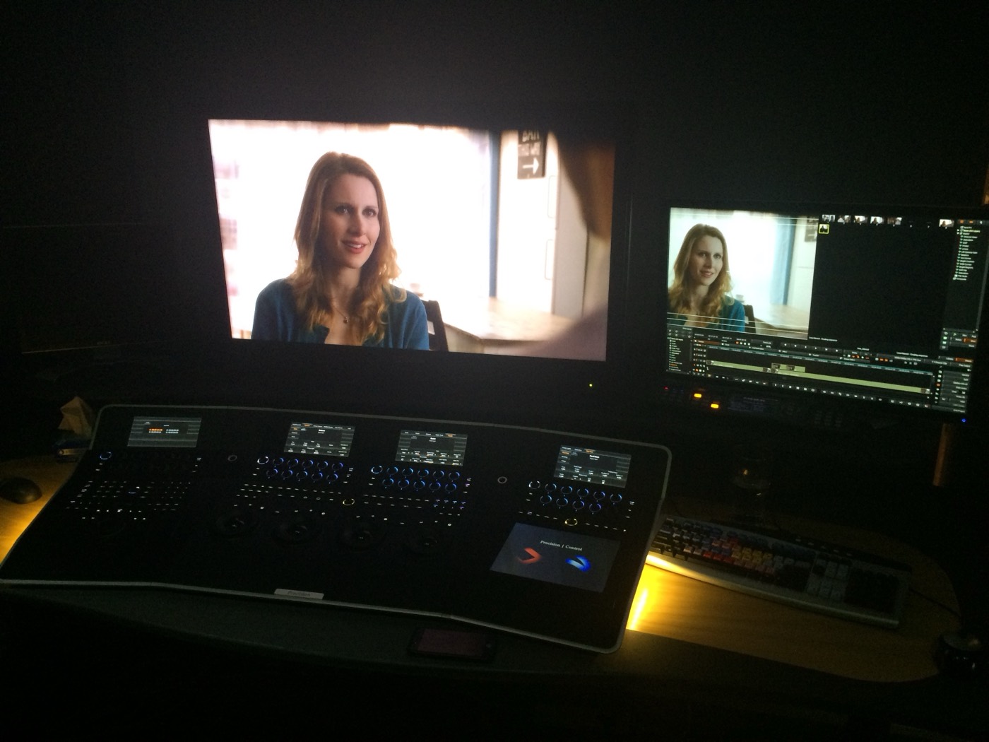 A color-grading suite: a control surface and reference monitors in a darkened room, where footage gets its final look.