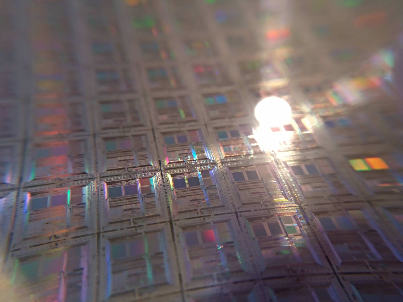 A silicon wafer, its dies catching the light. The race for cheaper generation increasingly runs through custom hardware.